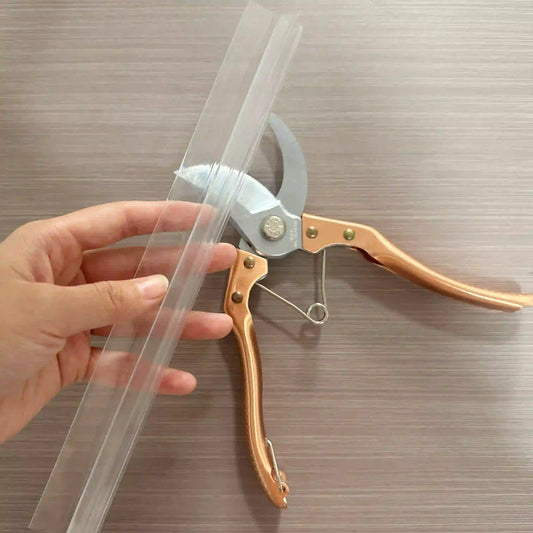 Using garden pruners to cut a white silicone shower door seal, ensuring straight edge for waterproofing