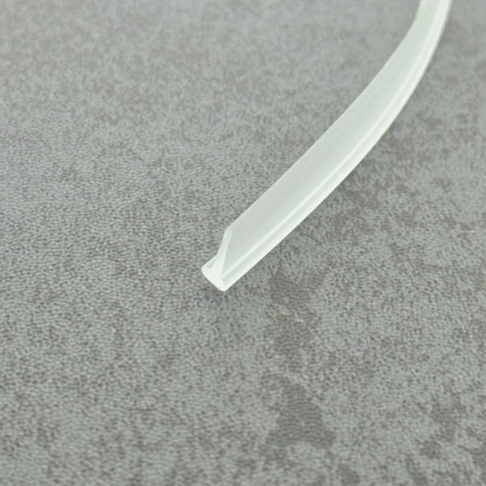 High-clarity close-up of a framed shower door seal strip (clear version), showcasing the high light transmission, smooth vinyl texture, and uniform T-shape structure of the VH001, highlighting its resistance to ageing as an ideal invisible accessory for modern minimalist framed shower enclosures.