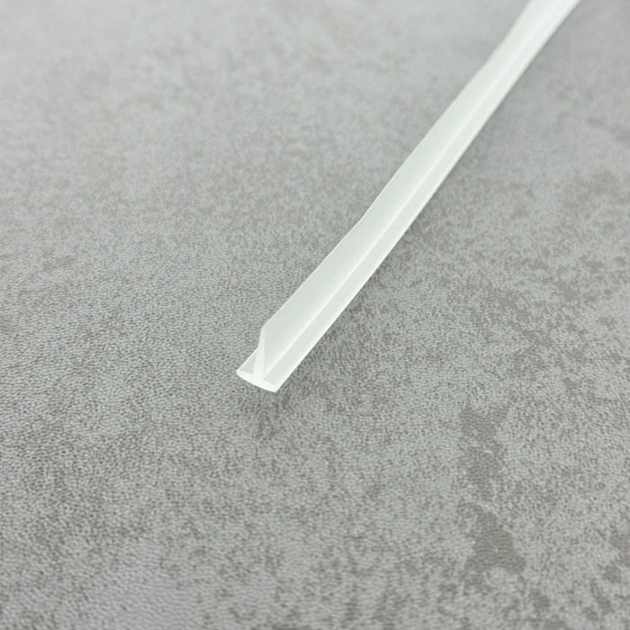 High-clarity close-up of a framed glass shower door seal (clear version), showcasing the high light transmission, smooth vinyl texture, and refined finish of the VH010's 8mm short fin, highlighting its low-profile design that blends seamlessly into modern glass shower enclosures, remaining virtually invisible without hindering door movement.