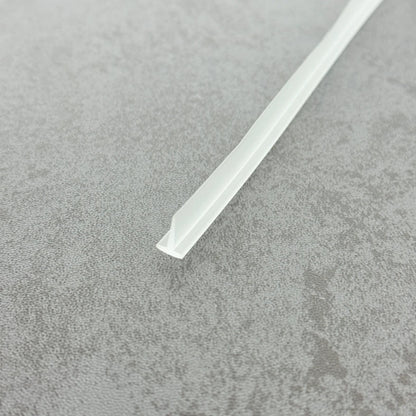 High-clarity close-up of a framed glass shower door seal (clear version), showcasing the high light transmission, smooth vinyl texture, and refined finish of the VH010's 8mm short fin, highlighting its low-profile design that blends seamlessly into modern glass shower enclosures, remaining virtually invisible without hindering door movement.
