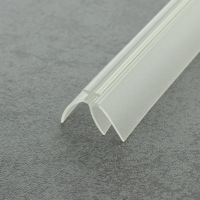 High-clarity close-up of a framed shower door bottom seal strip (clear version), showcasing the high light transmission, smooth vinyl texture, and exceptional flexibility of the VE02's complex triple-fin structure, highlighting its resistance to ageing as an effective substitute for failed old seals to provide a triple waterproof barrier while remaining virtually invisible beneath the glass door to maintain bathroom aesthetics.