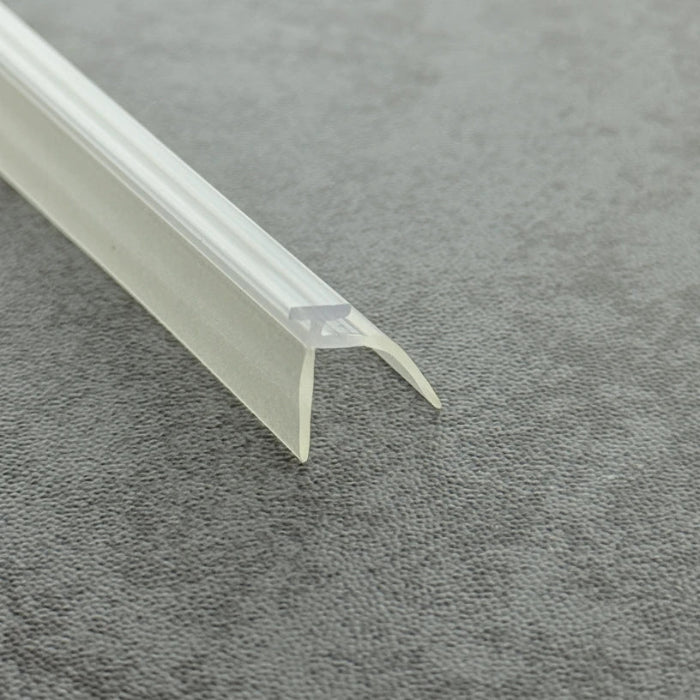 High-clarity close-up of a framed shower door replacement drip rail with vinyl sweep (clear version), showcasing the high light transmission, smooth vinyl texture, and exceptional flexibility of the VE03's dual-fin structure, highlighting its resistance to ageing as an effective substitute for yellowed or hardened old rails to provide a dual waterproof barrier while remaining virtually invisible beneath the glass door.