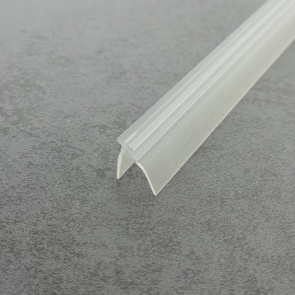 High-clarity close-up of a shower door frame gasket (clear version), showcasing the high light transmission, smooth vinyl texture, and flexibility of the VE01's complex profile (including the side rail), highlighting its resistance to ageing as an effective substitute for hardened or failed old gaskets to provide dual-layer protection while remaining virtually invisible beneath the glass door.