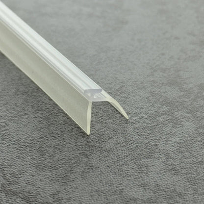 Micro-view of a shower screen frame seal, showing how the T-head and extended side rail work in tandem; while the main fin contacts the floor, the side rail captures and channels sideways splashes running down the glass, providing a comprehensive waterproof barrier at the base of framed shower screens to help reduce the risk of slippery bathroom floors.