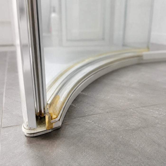Close-up of an old yellowed shower door seal needing a replacement