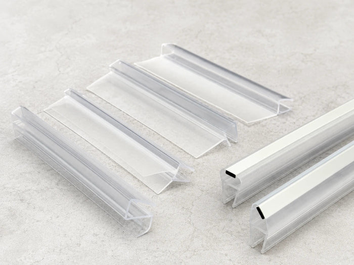 Clear PVC shower door seal with water droplets and testing tools on a light background